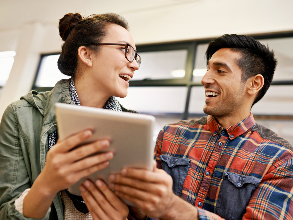 man and women looking at each other while holding tablet device