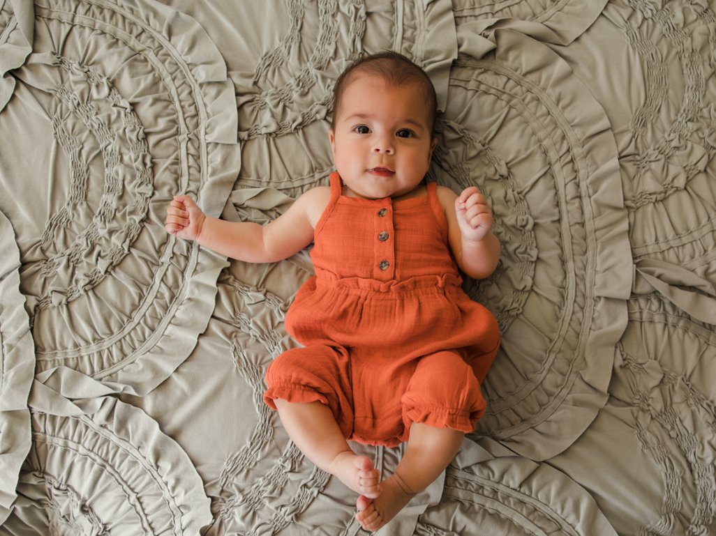 An infant baby lying on a bed, smiling 