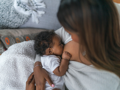 mother holding baby while baby breastfeeds