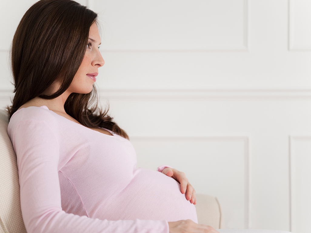 pregnant woman with hand on belly looking off into the distance