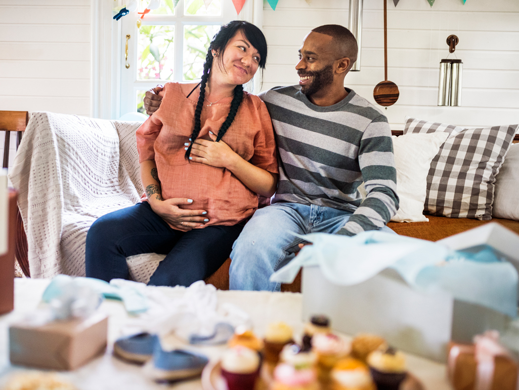 A pregnant woman and a man sitting next to each other on a couch
