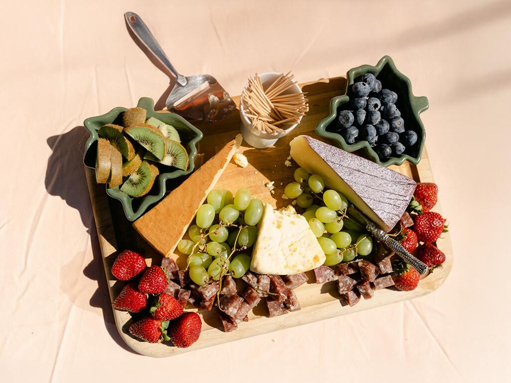 overhead view of a charcuterie platter with soft cheeses, meat, and fruit