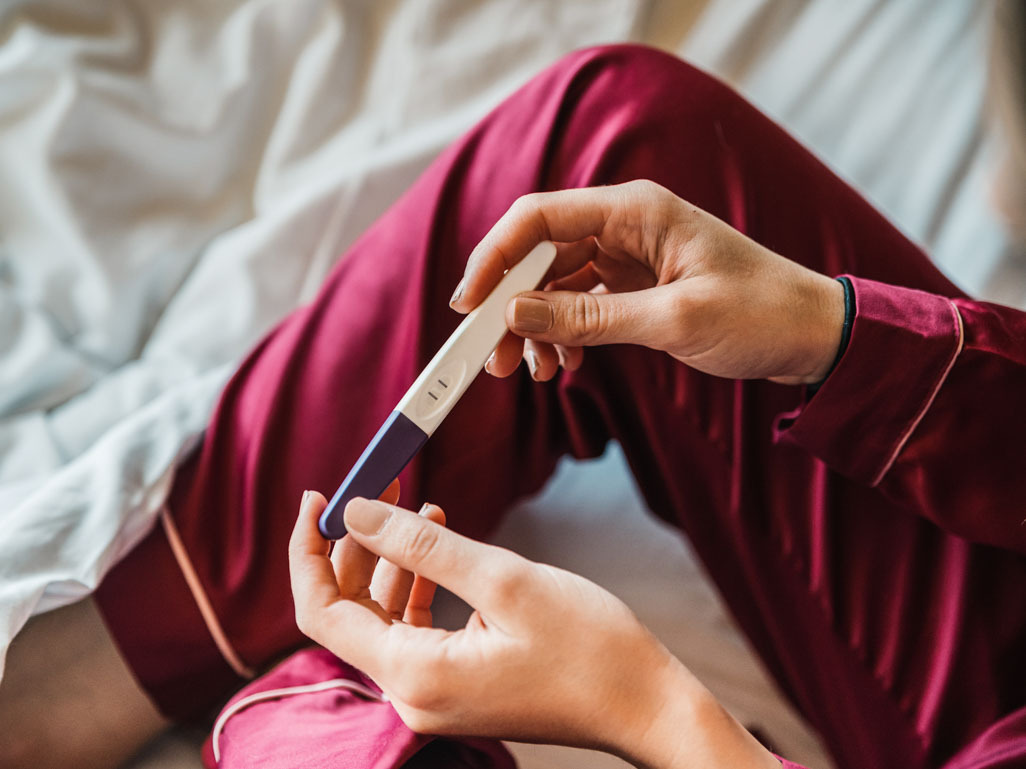 Woman in pajamas with positive pregnancy test