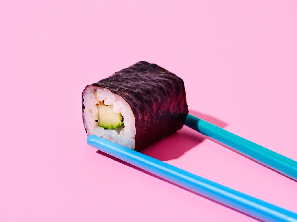 blue chopsticks holding an avocado roll