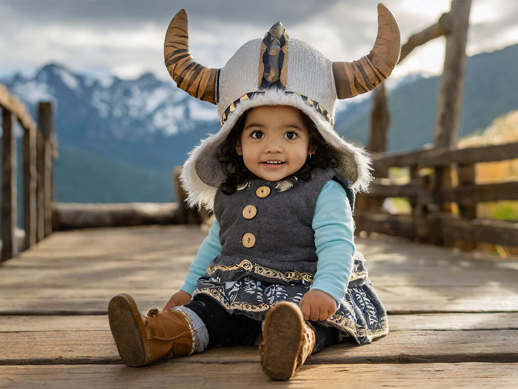 A baby wearing a Viking-style outfit and helm