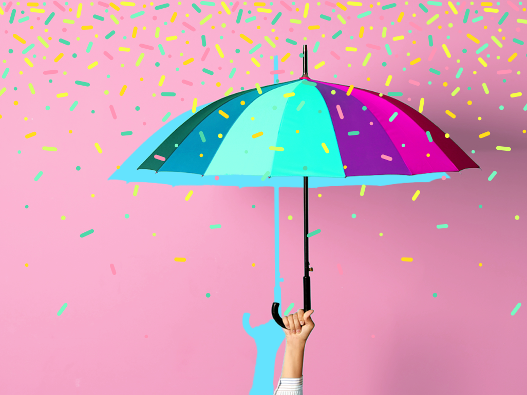 hand holding up a blue and pink umbrella with sprinkles raining down around it
